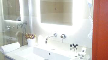 Un baño con un lavabo blanco grande, un espejo y una cabina de ducha de vidrio.