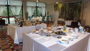 A dining area with tables set for a meal, featuring a variety of dishes and a decorative centerpiece. - MajesticHouse Conference & Restaurant (Castenedolo)
