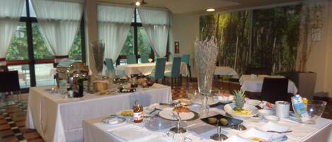 A dining area with tables set for a meal, featuring a variety of dishes and a decorative centerpiece.