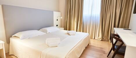 A hotel room with a large bed, a desk, and a chair.