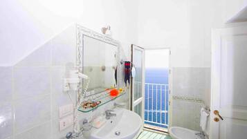 A bathroom with a large mirror, a sink, and a shower.