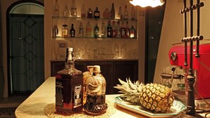 Een bar met verschillende drankflessen, een ananas op een bord en een waterpijp.