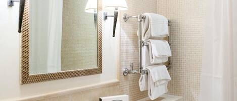 A bathroom with a sink, mirror, towel rack, and shower curtain.