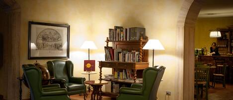 Une bibliothèque chaleureuse, avec des fauteuils en cuir, une table en bois et une bibliothèque remplie de livres.