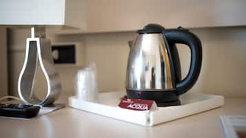 Un comptoir de cuisine avec une bouilloire, une télécommande et une bouteille d’eau.