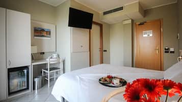 A hotel room with a bed, a desk, a television, and a small refrigerator.