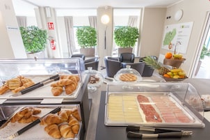 Um buffet de café da manhã com pães, frutas e frios.