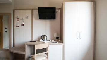 Een hotelkamer met een bed, een bureau met stoel, een wandtelevisie en een kledingkast.