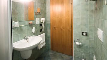 Ein Badezimmer mit Waschbecken, Spiegel, Handtuchhalter und einer Holztür.