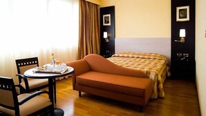 Quarto de hotel com uma cama, um sofá, uma mesa com uma bandeja de itens de café da manhã e uma cadeira.