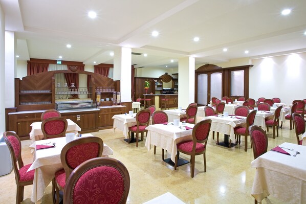 A dining area with multiple tables and chairs, a bar area, and a kitchen in the background.