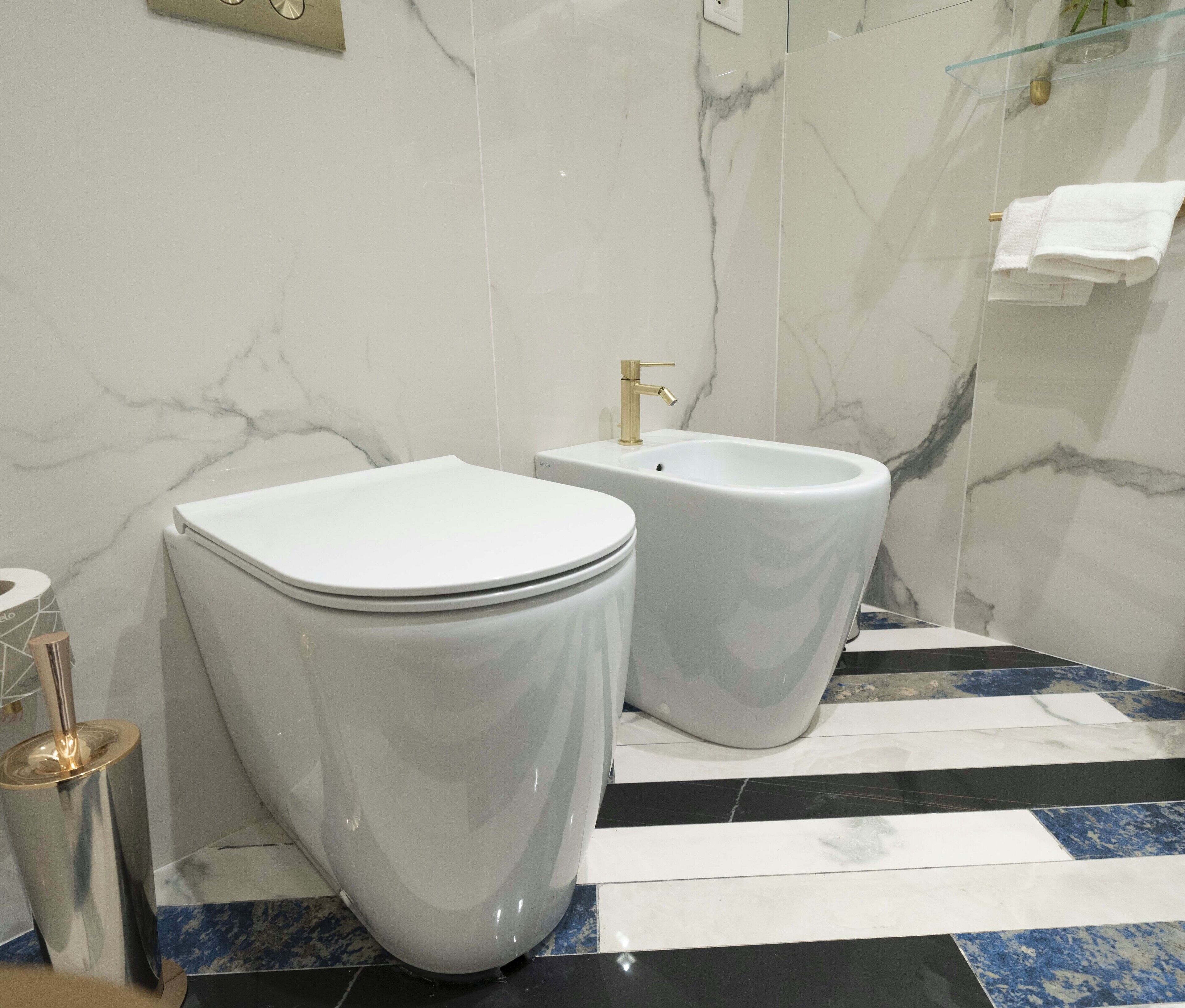 A bathroom with two toilets, a sink, and a glass shower enclosure.