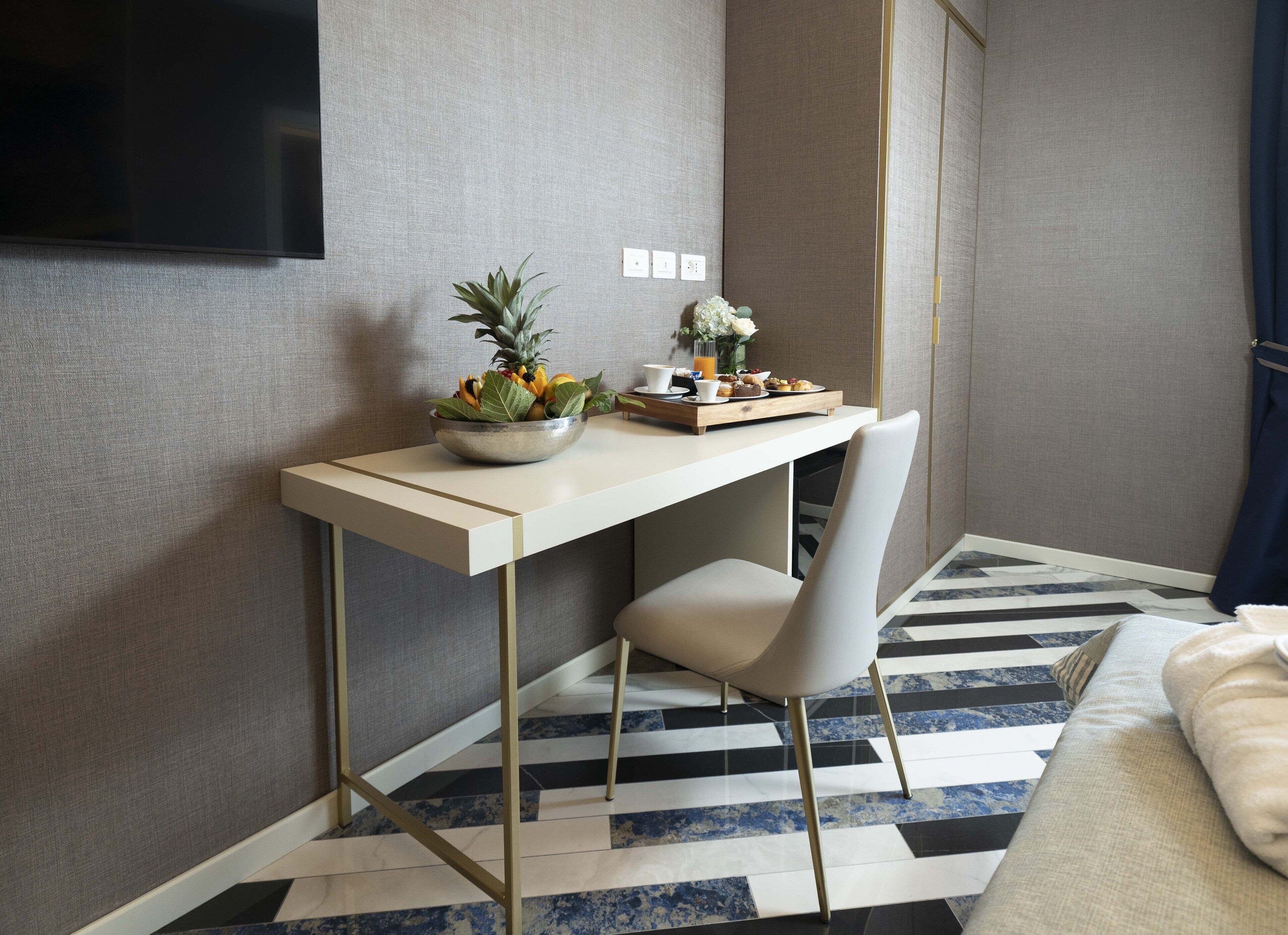 Ein Hotelzimmer mit Schreibtisch, Stuhl, Bett, Fernseher und einem gemusterten Boden.