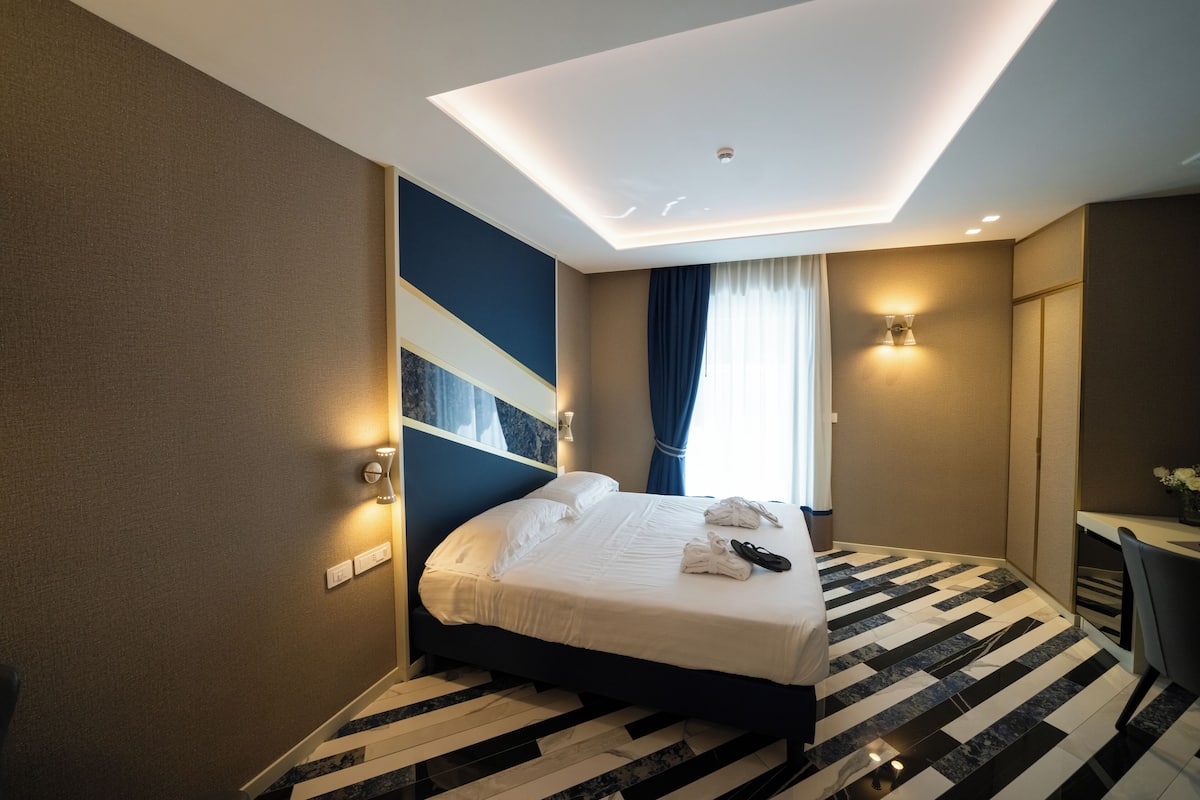A hotel room with a bed, a desk, and a chair.
