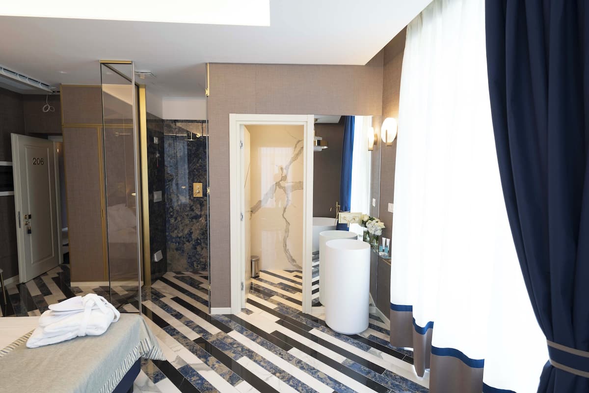 A modern hotel bathroom with a shower, a large sink, and a mirror.