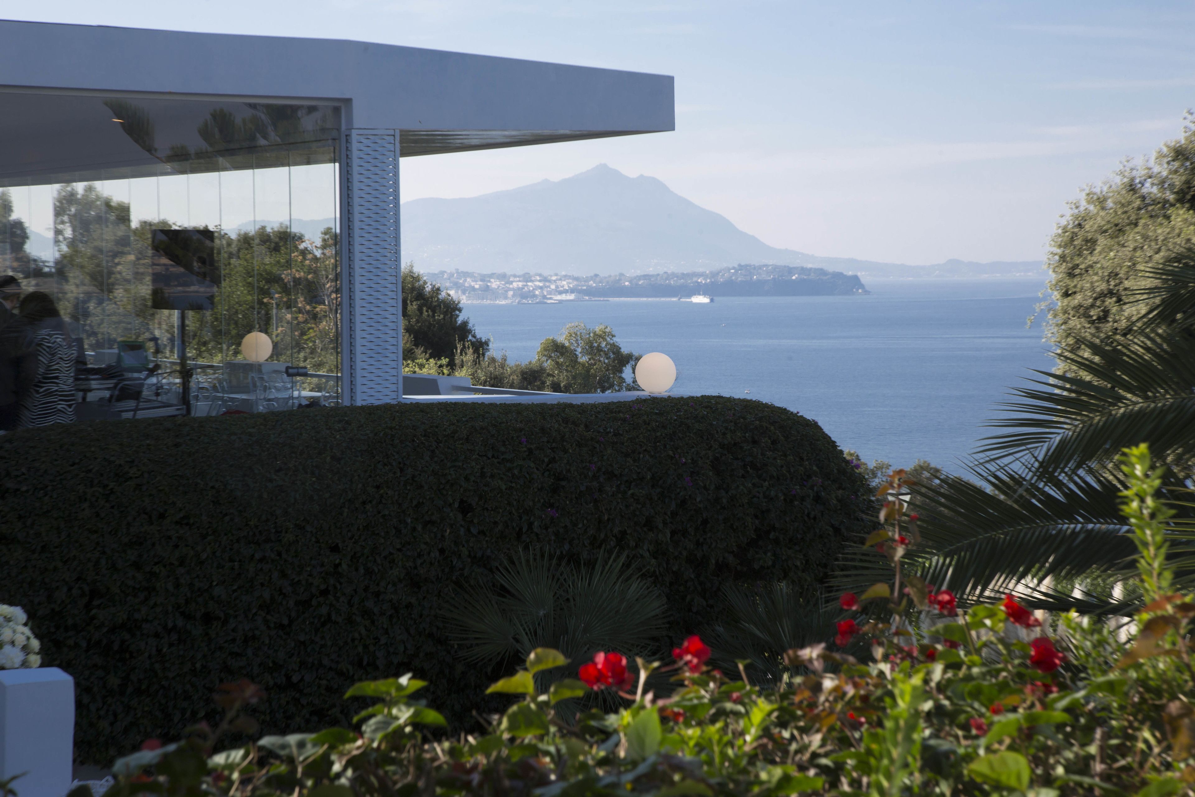 Un edificio moderno con fachada de vidrio que ofrece vistas a un cuerpo de agua y una montaña.