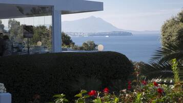 A modern building with a glass facade overlooking a body of water and a mountain.