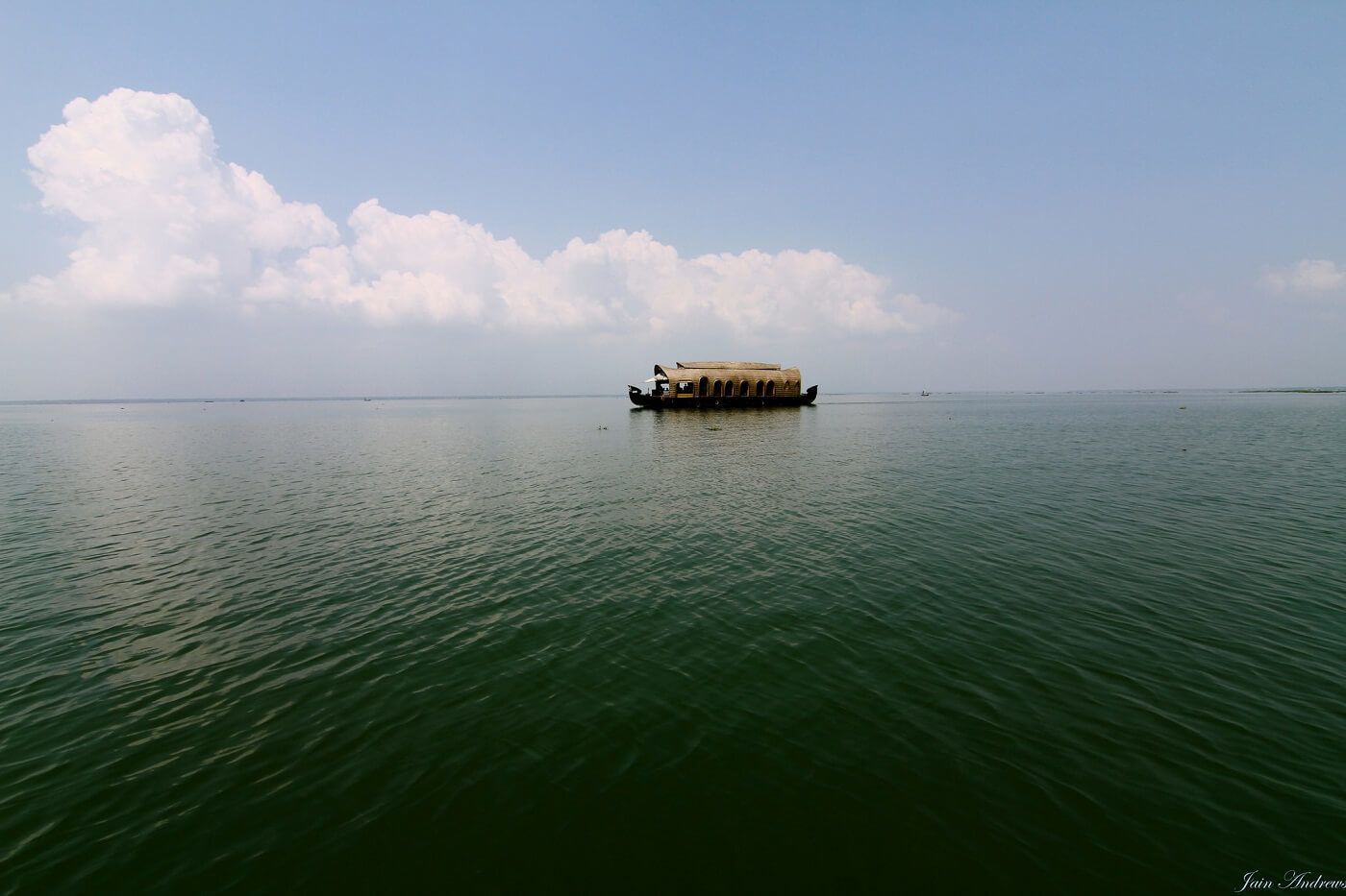 Ein Boot mit einem Reetdach auf ruhigem Wasser.