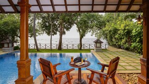A wooden deck with a pool, two chairs, and a table with drinks. - The Zuri Kumarakom Kerala Resort & Spa (Kottayam)