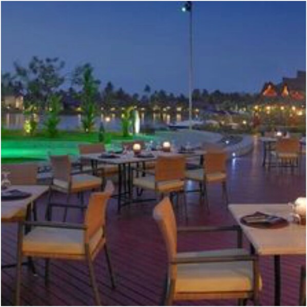 An outdoor dining area with tables and chairs, a pool, and a view of the surrounding landscape.
