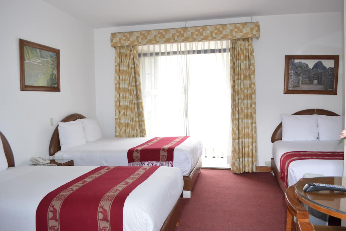 A hotel room with two beds, a large window with curtains, a painting on the wall, and a remote control on a table.