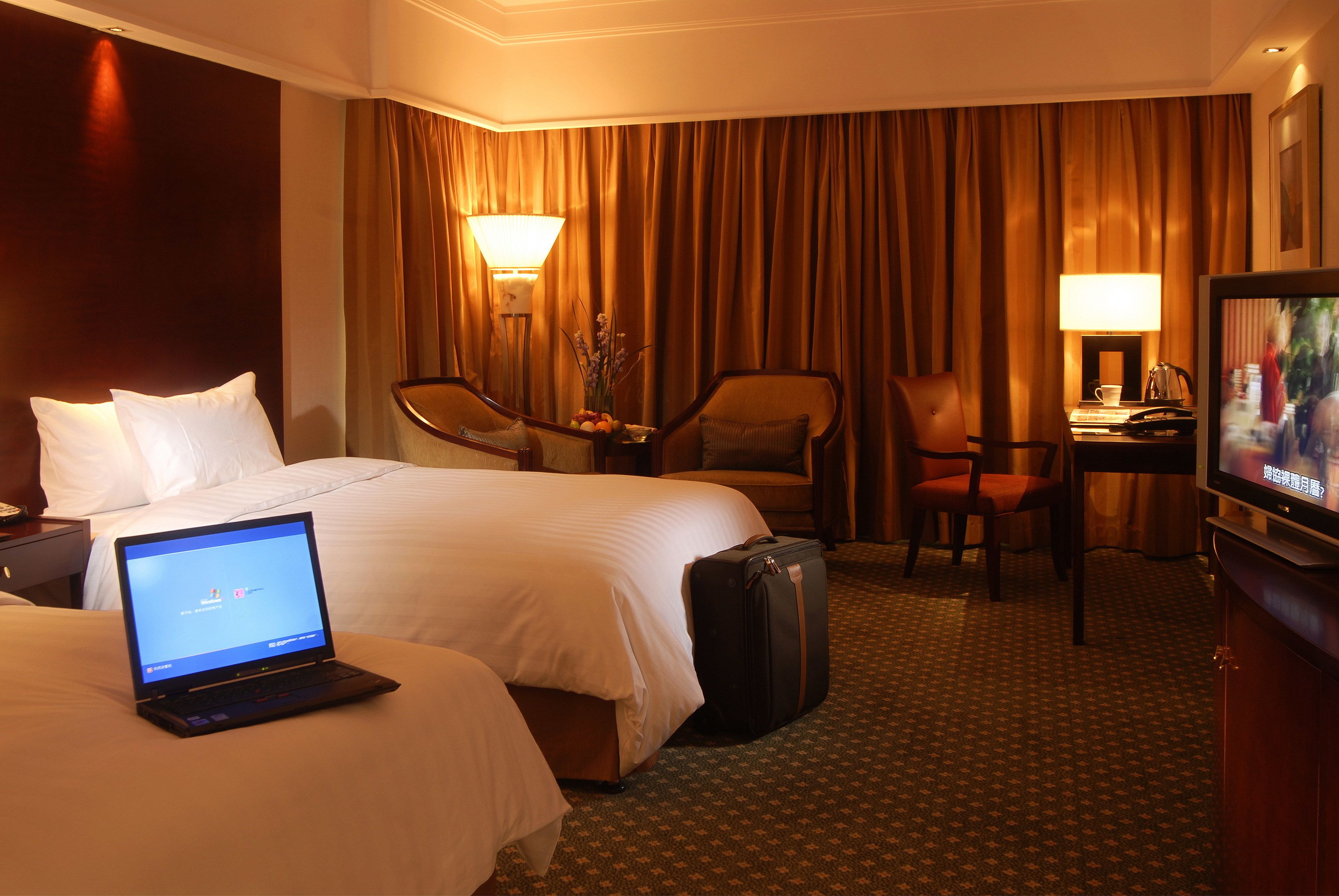 Una habitación de hotel con una cama, un escritorio, una silla, un televisor y una computadora portátil.