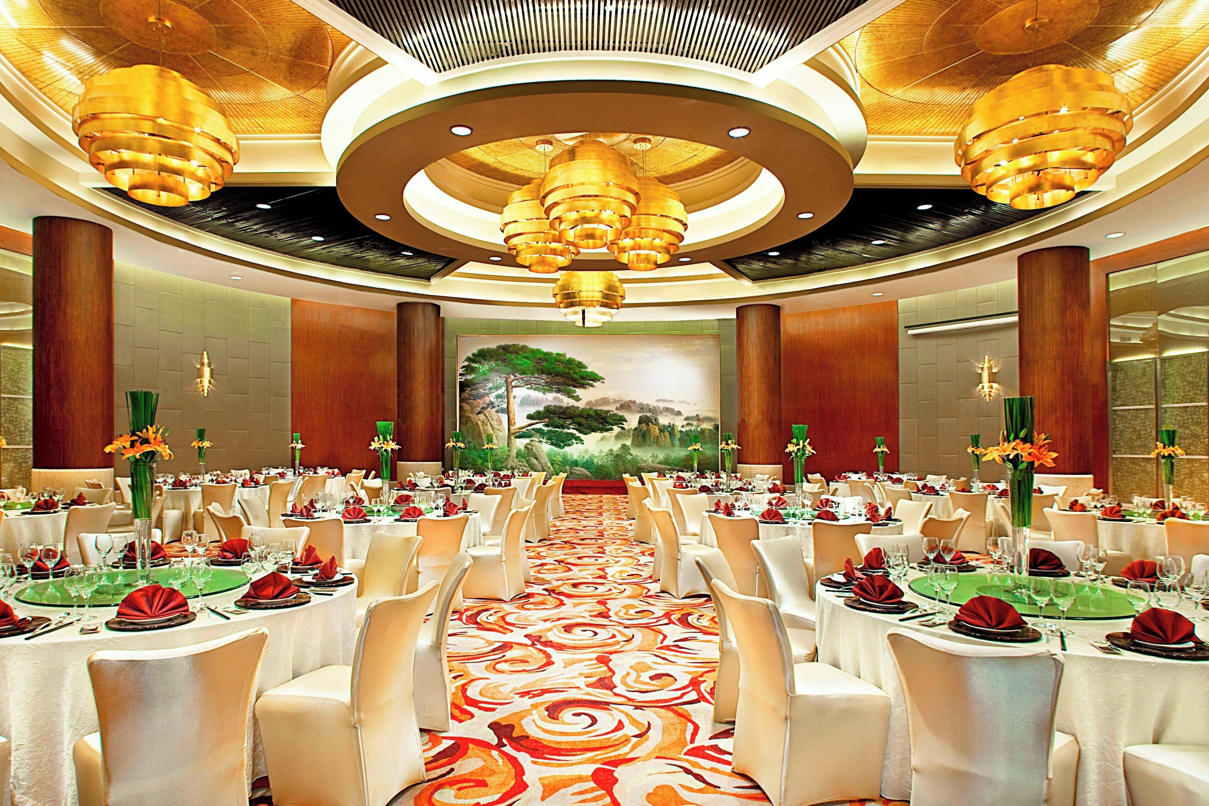 Une salle de banquet avec des tables rondes, des chaises blanches et une allée centrale.