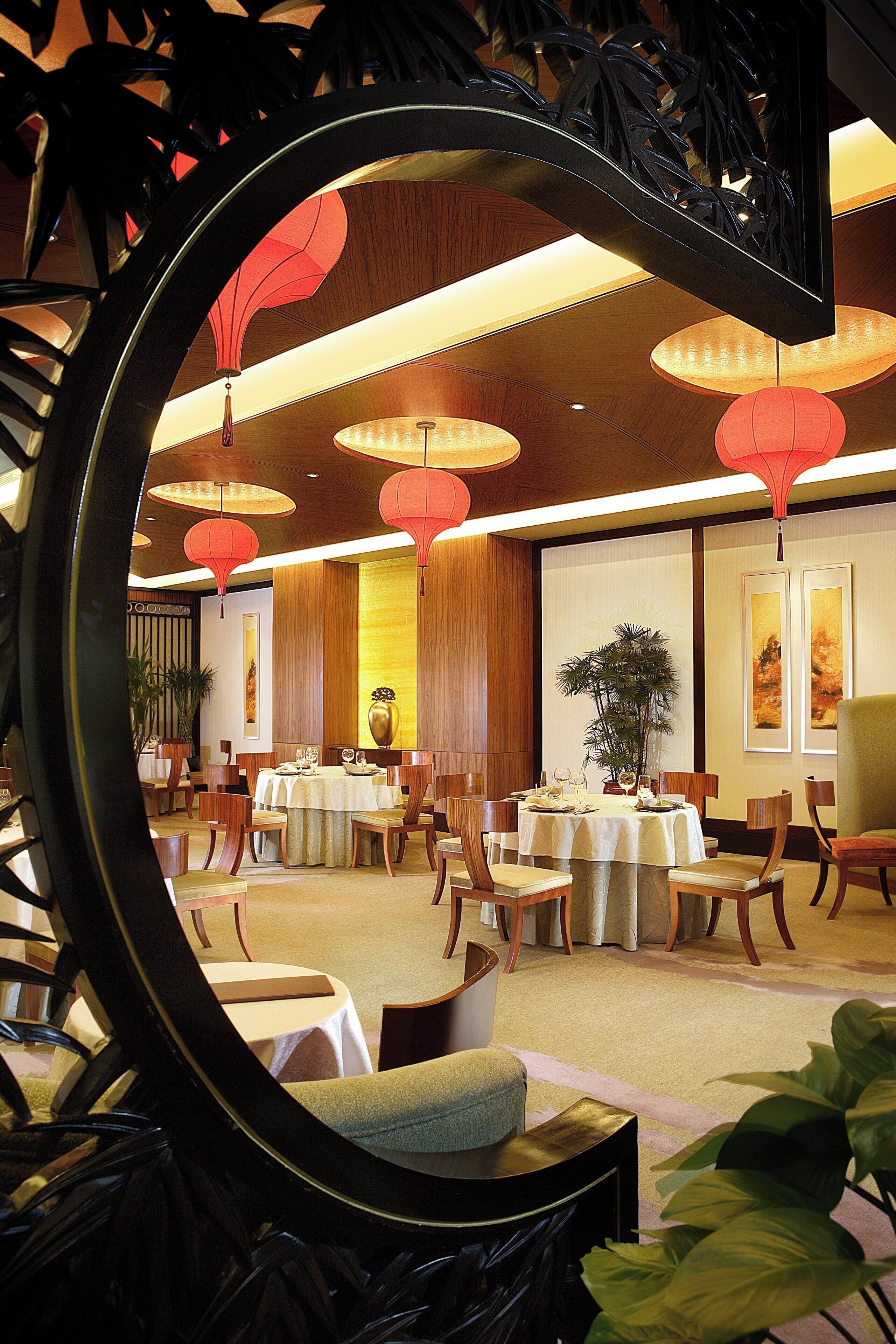 A dining area with round tables, chairs, and red lanterns.