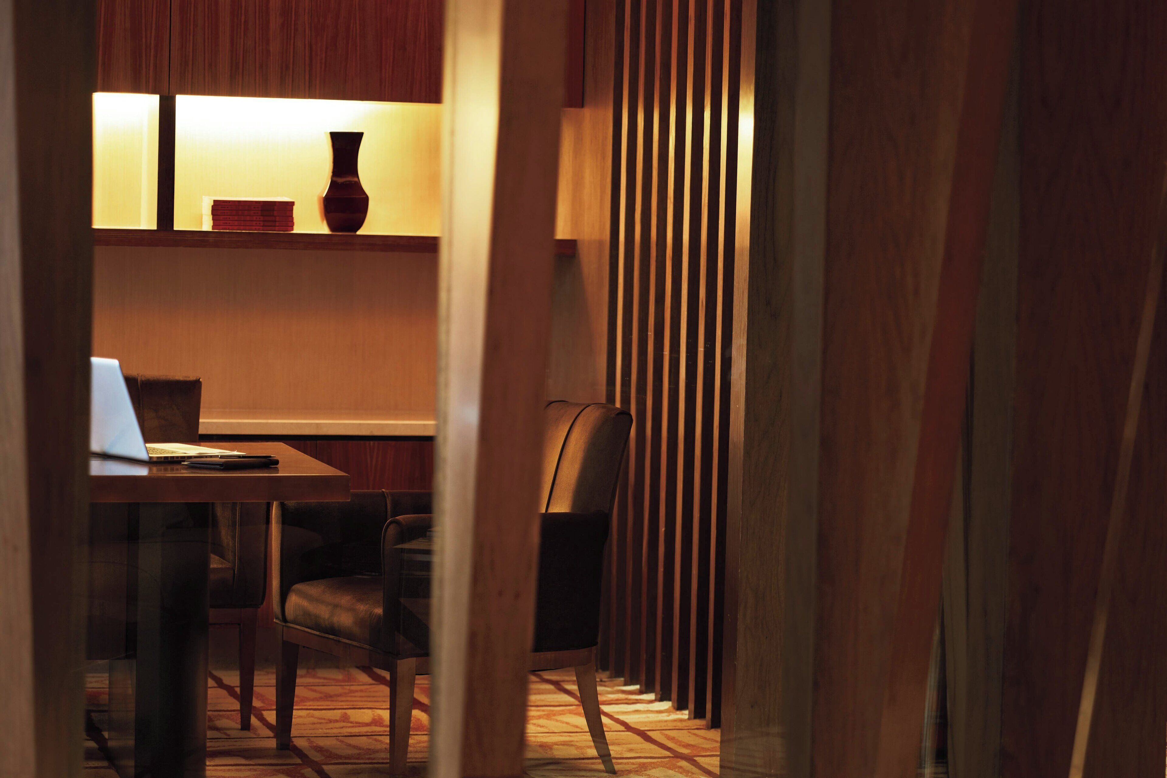A modern dining area with a wooden table, chairs, and a laptop.
