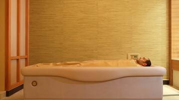 A massage therapy bed in a room with wooden paneling and a wooden floor.