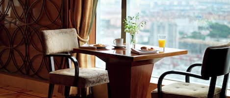 A dining area with two chairs, a table, a vase with flowers, a plate with food, and a glass of orange juice.