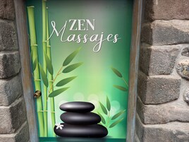 Una puerta con la inscripción “ZEN Massages” y un diseño decorativo con bambú y piedras.