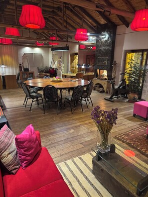 A spacious living area with a wooden dining table, red cushions, and a glass coffee table.
