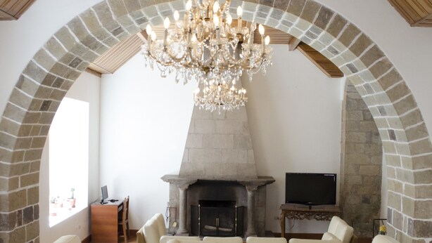 A cozy living room with a stone fireplace, a chandelier, and comfortable seating. - Hotel Garcilaso I (Cusco)