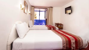 A hotel room with two beds, a view of the city at night, and a small table with a lamp. - Hotel Garcilaso I (Cusco)