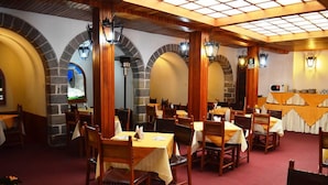 A restaurant with wooden tables and chairs, stone arches, and warm lighting. - Hotel Garcilaso I (Cusco)