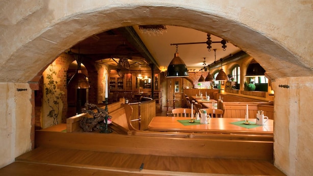 An underground restaurant with wooden tables, hanging lights, and brick walls. - Villa Knobelsdorff (Pasewalk)
