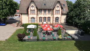 A hotel with a traditional architectural style, featuring a central courtyard with outdoor seating and umbrellas. - Villa Knobelsdorff (Pasewalk)