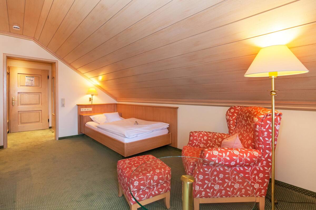 A room with a bed, a chair, and a lamp.