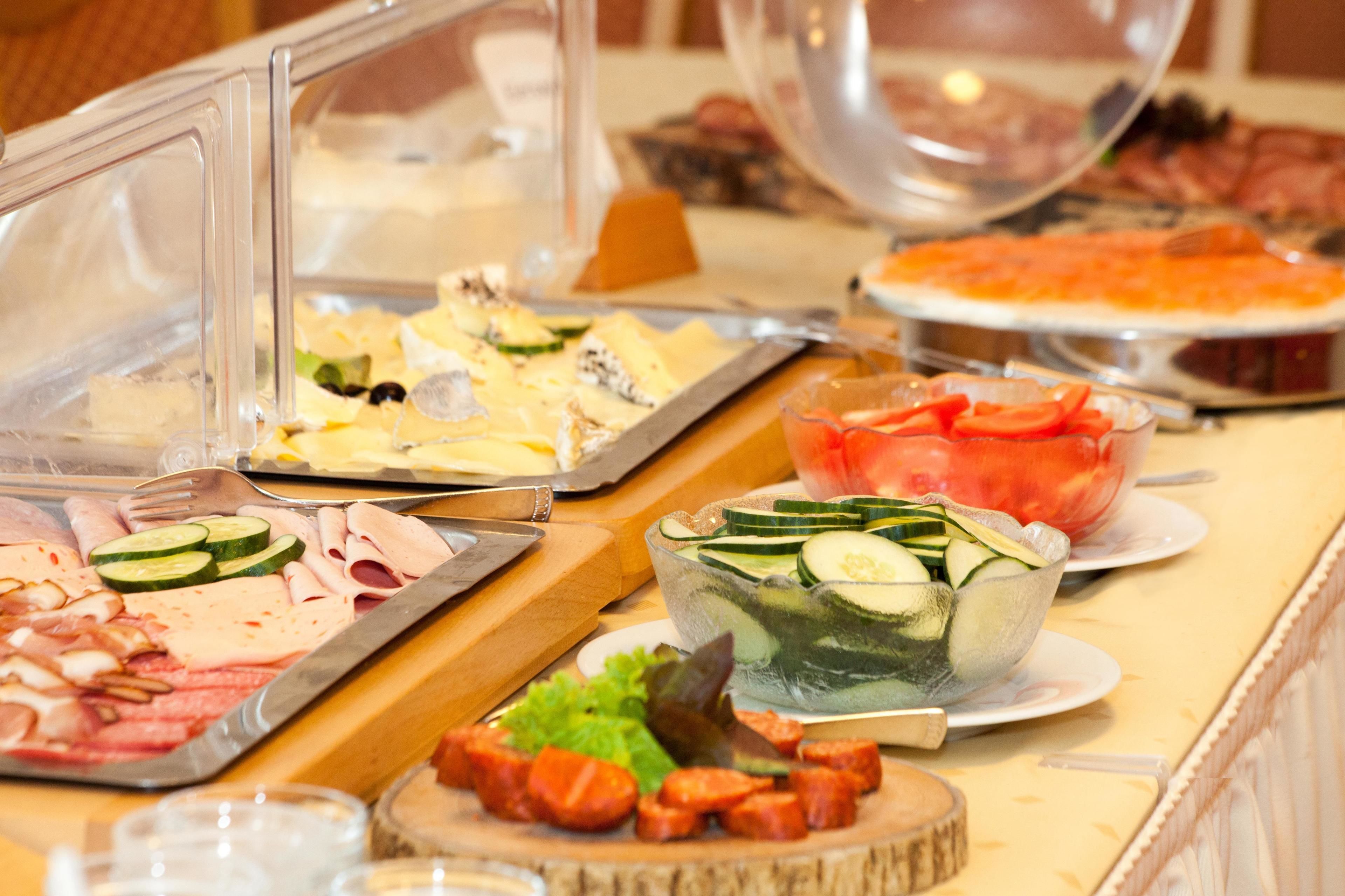 A buffet with various food items including meats, cheeses, and salads.