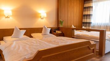 Une chambre d’hôtel avec deux lits en bois, une table de chevet avec un téléphone et un miroir au-dessus des lits.