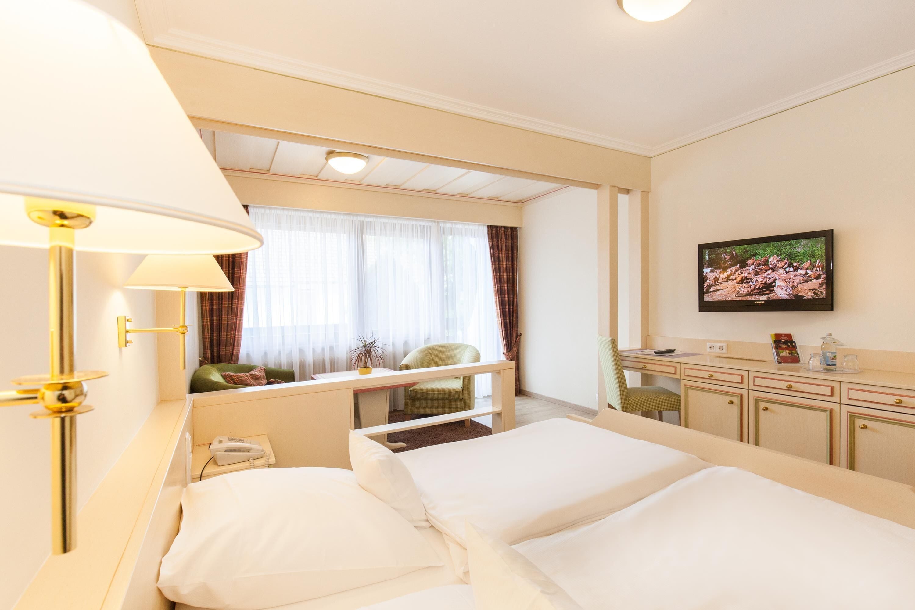 Habitación de hotel con dos camas, un escritorio, una silla, un televisor y una lámpara.