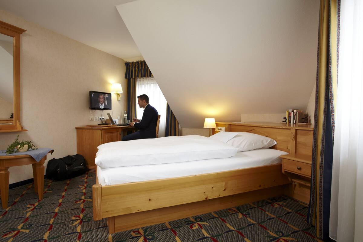 A hotel room with a bed, desk, television, and a small table.