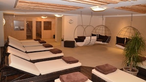 A spa room with multiple massage tables, a hanging chair, and a potted plant. - Landgasthof Hotel Hirsch (Lossburg)