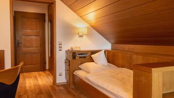 Ein Schlafzimmer mit Holzboden, einem Bett mit weißer Bettwäsche, einem Nachttisch und einer Wandlampe.