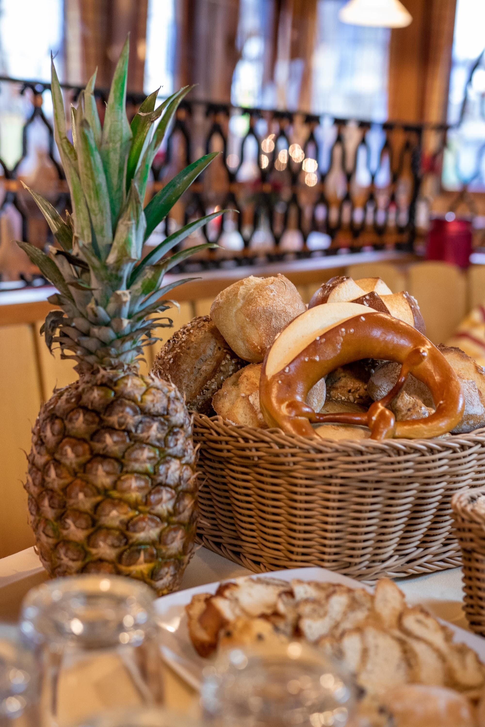 A table with a pineapple, pretzels, and bread.