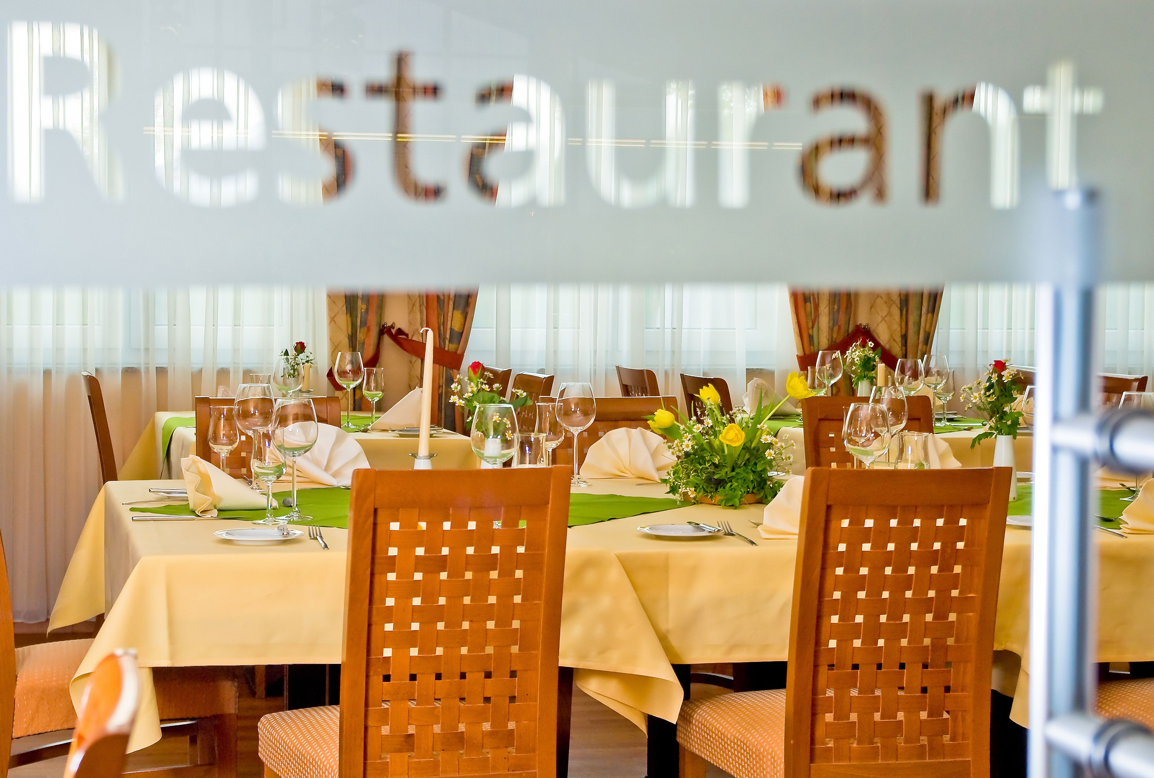 A restaurant with tables set for dining, complete with cutlery and glassware.