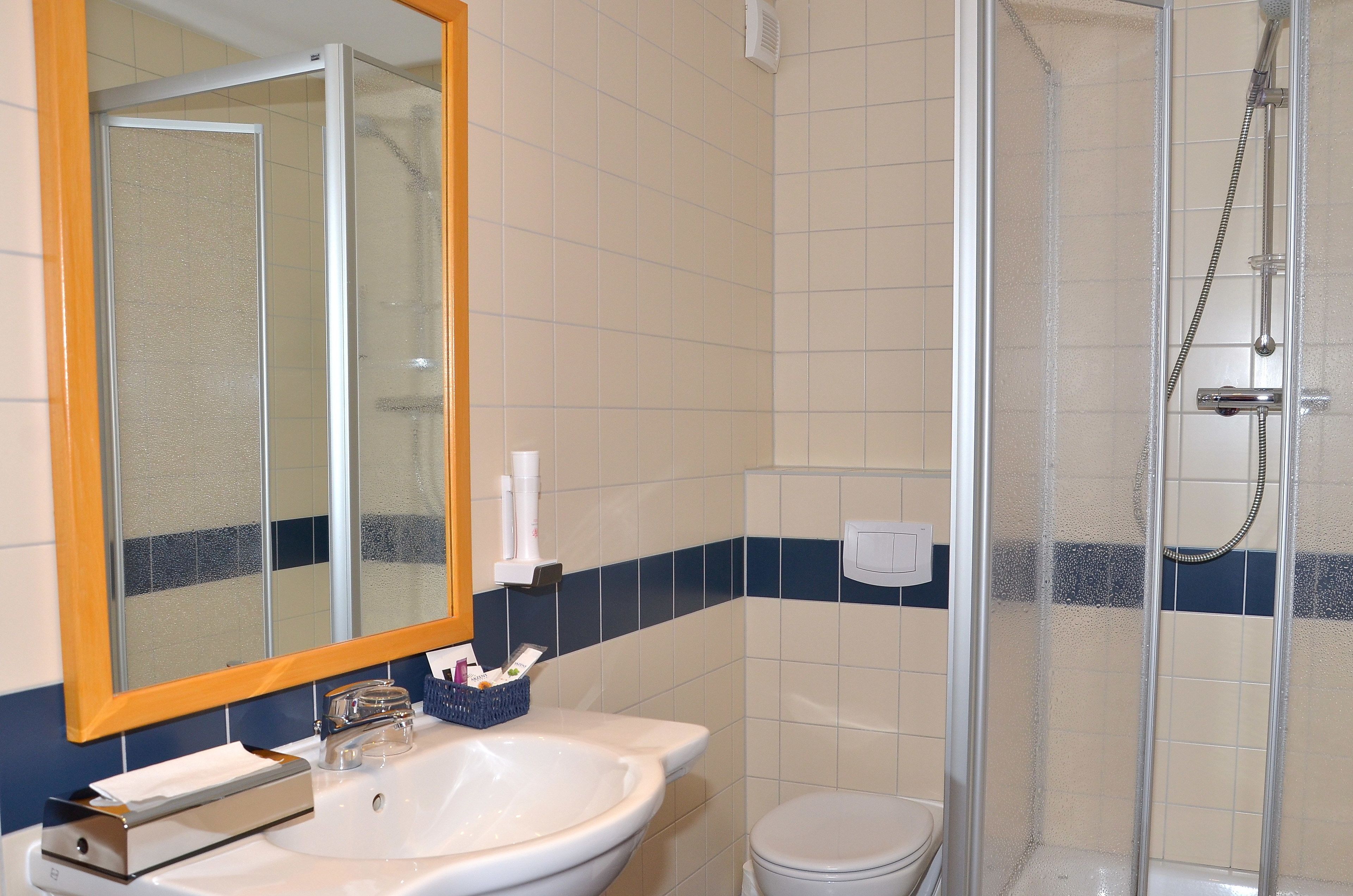A bathroom with a white sink, mirror, and shower enclosure.