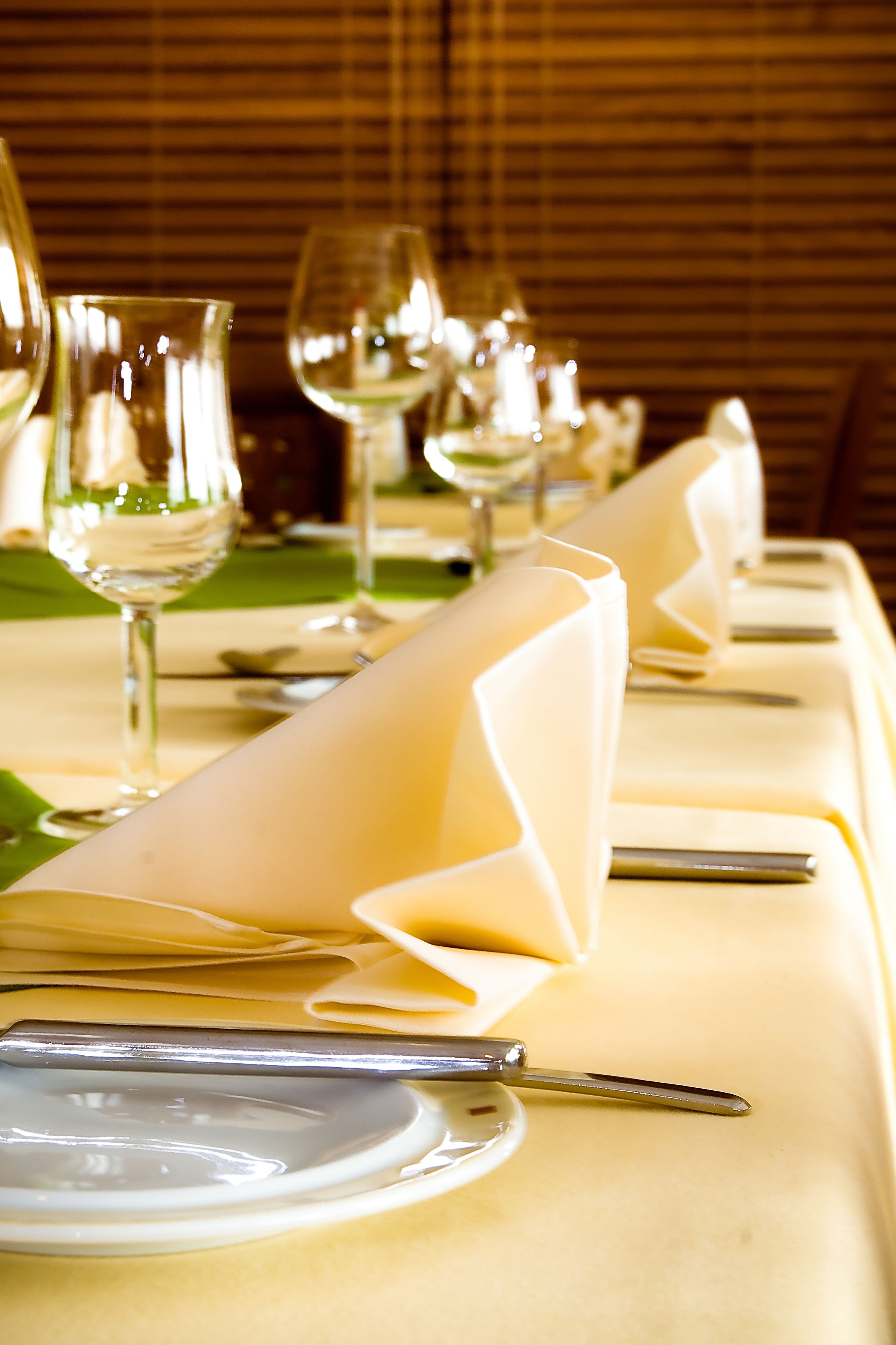 Mesa dispuesta para comer, con servilletas blancas, cubiertos y copas de vino.