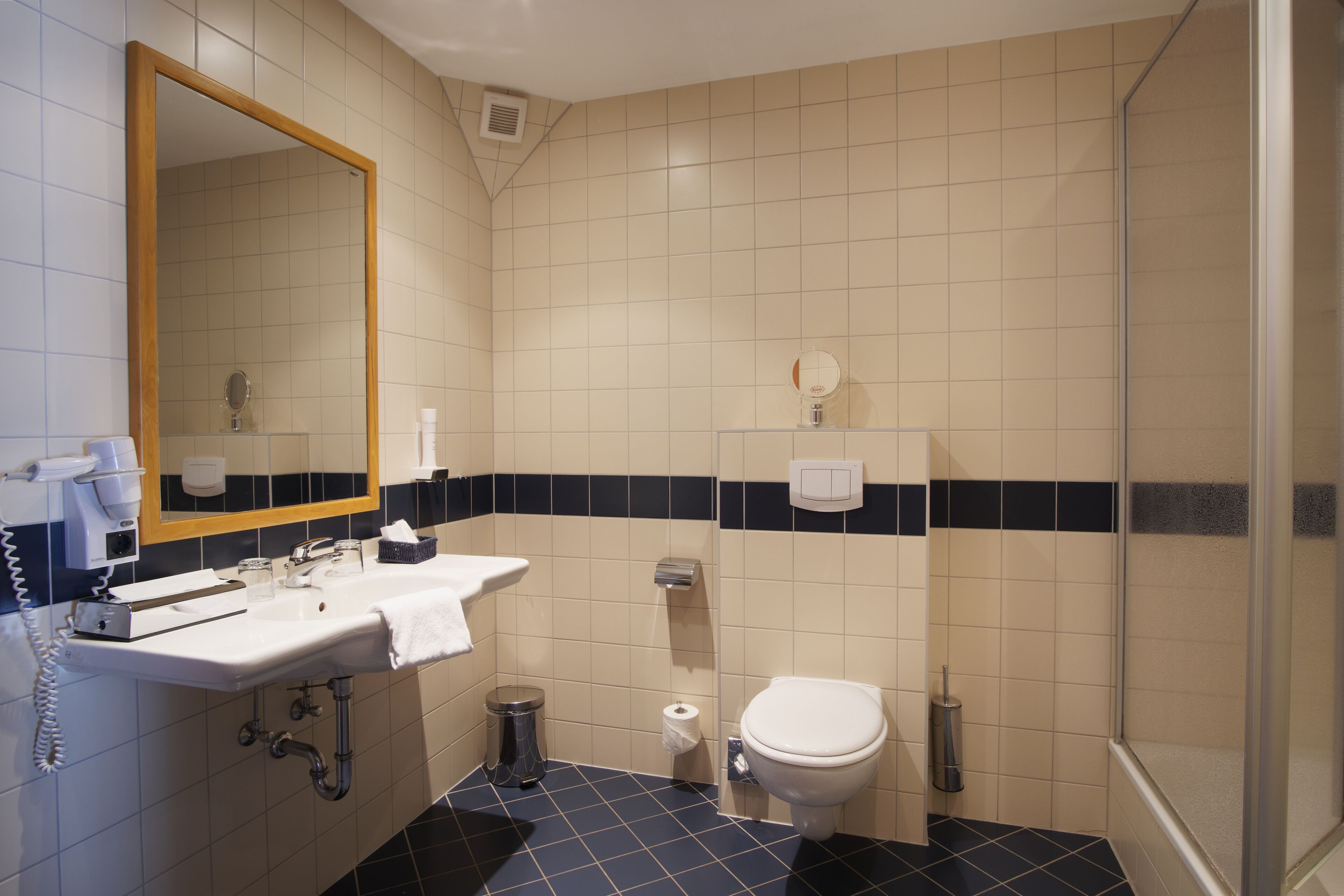 A bathroom with a sink, mirror, toilet, and shower.
